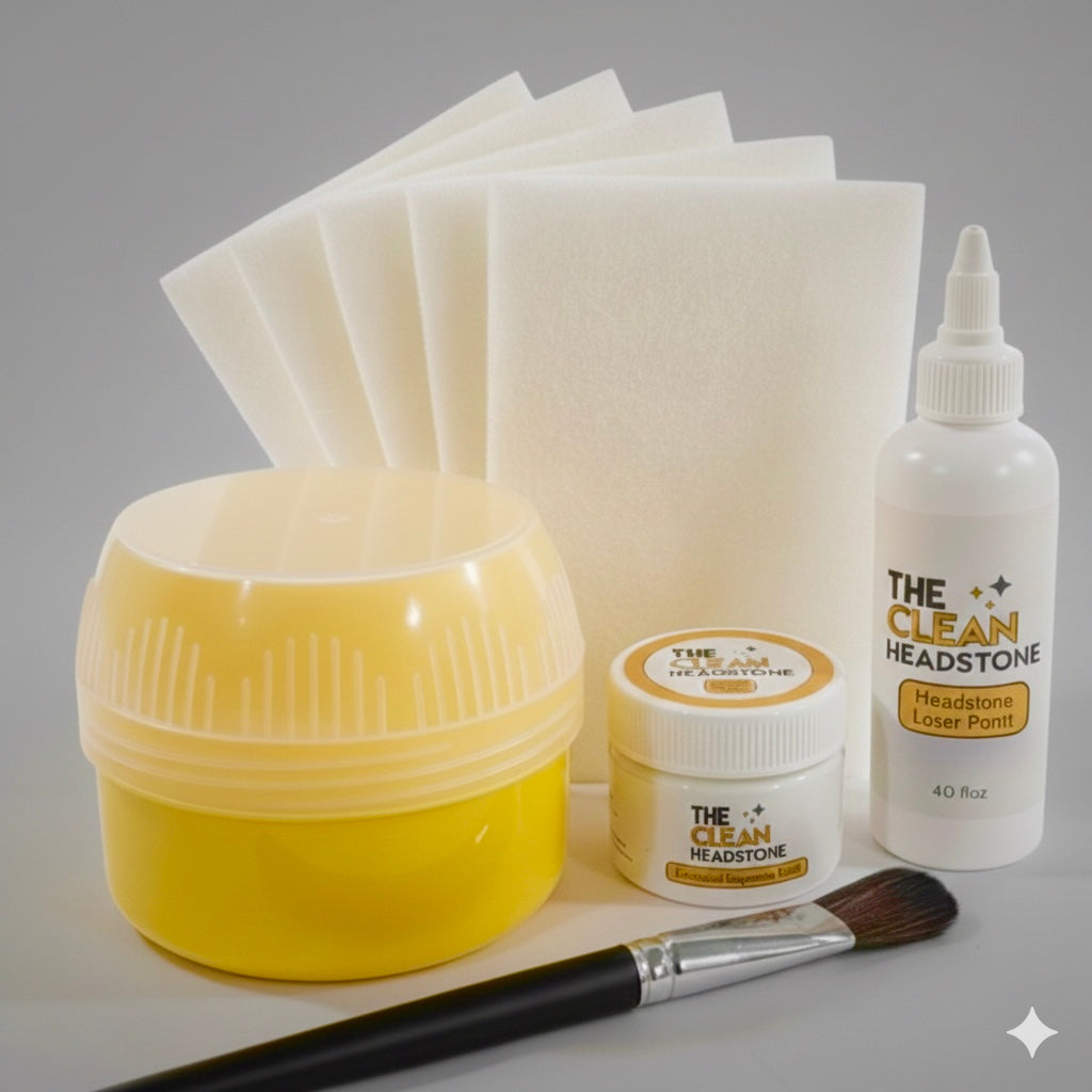 Collection of 'The Clean Headstone' cleaning and maintenance products including a yellow jar, white bottle, brush, and cloths on a gray background.